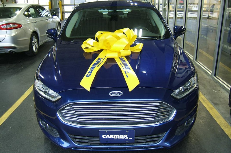 Blue Ford Fusion with a yellow bow on the hood