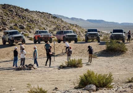 Broncos in desert with people golfing