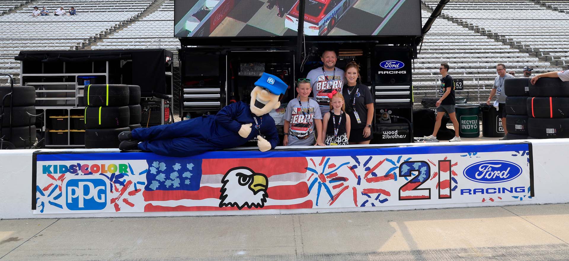 Kid and family on pit row in front of banner