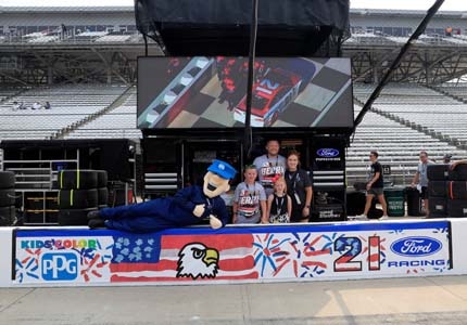 Kid and family on pit row in front of banner