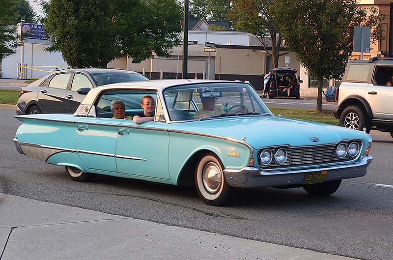 light blue thunderbird driving on road