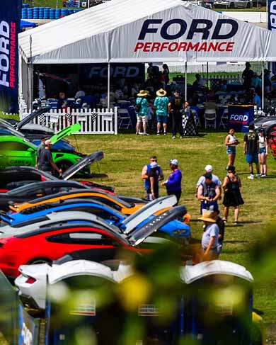 Ford mustang cars around a tent at a motorsports event.
