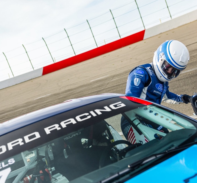 Race car driver behind the wheel, door opened, talking to another man