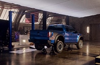 A blue raptor in a garage raised on a mount