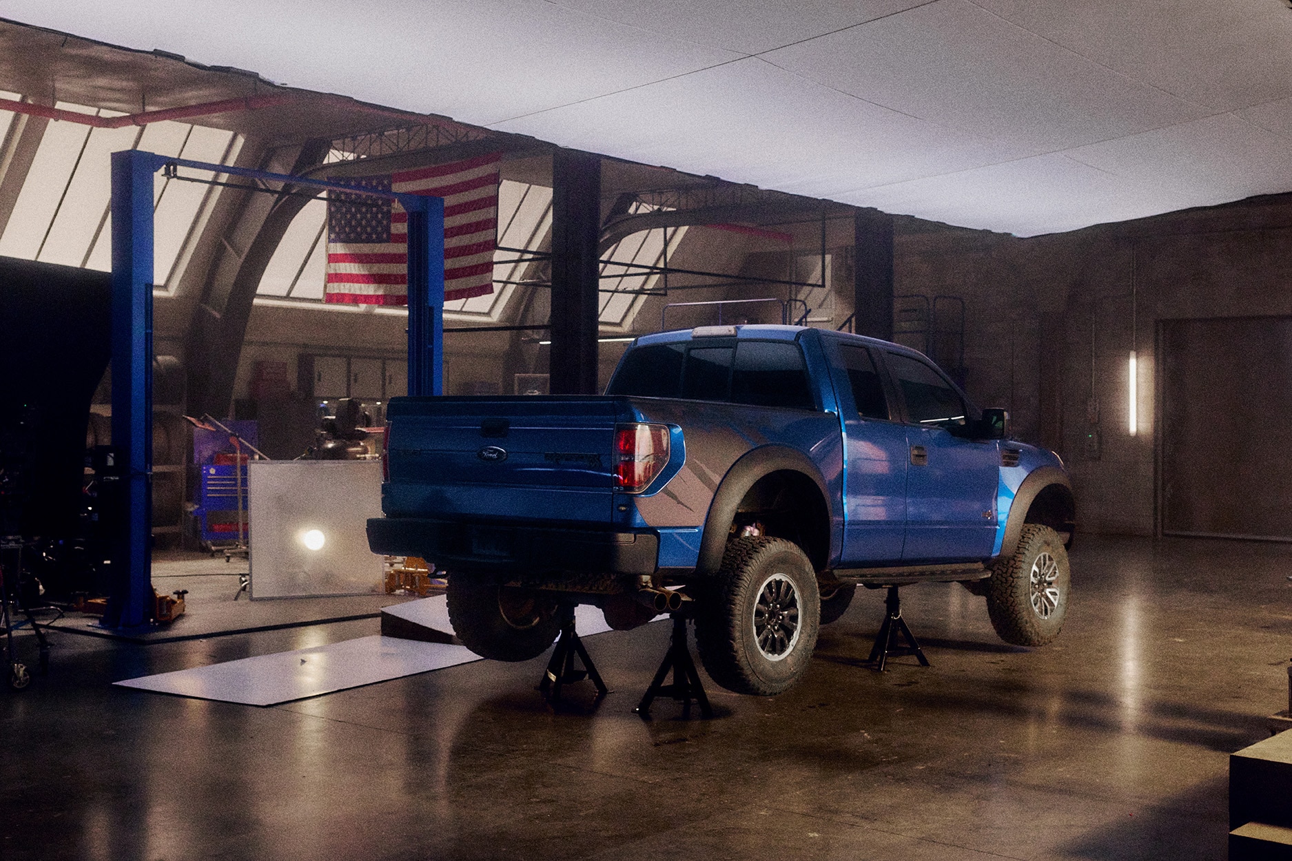 A blue raptor in a garage raised on a mount