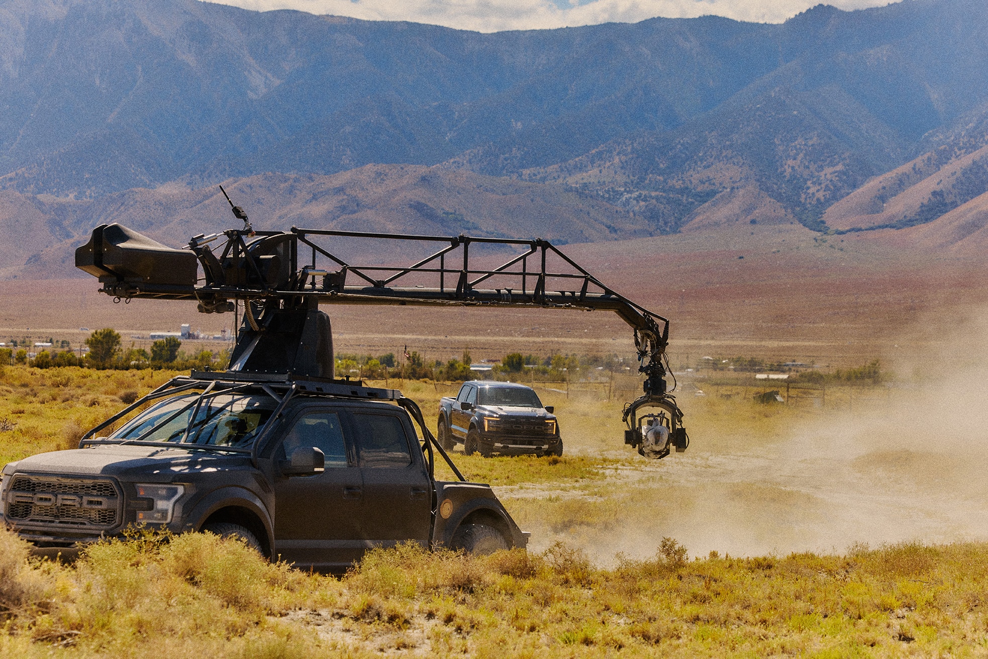 A movie camera mounted on a truck filming a Ford Raptor behind it