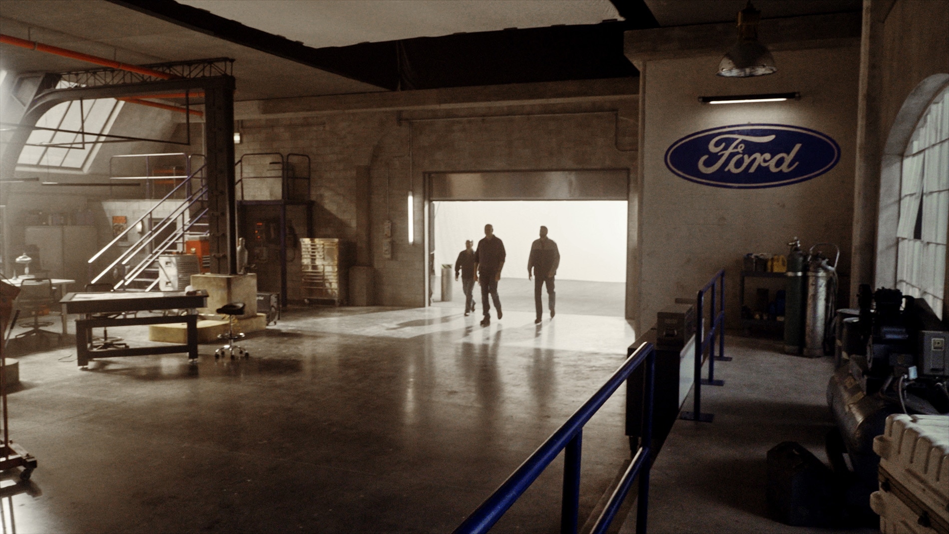Wide angle shot of Ford Racing engineers walking into a garage backlit by daylight