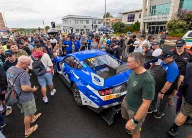 Race car driver behind the wheel, door opened, talking to another man