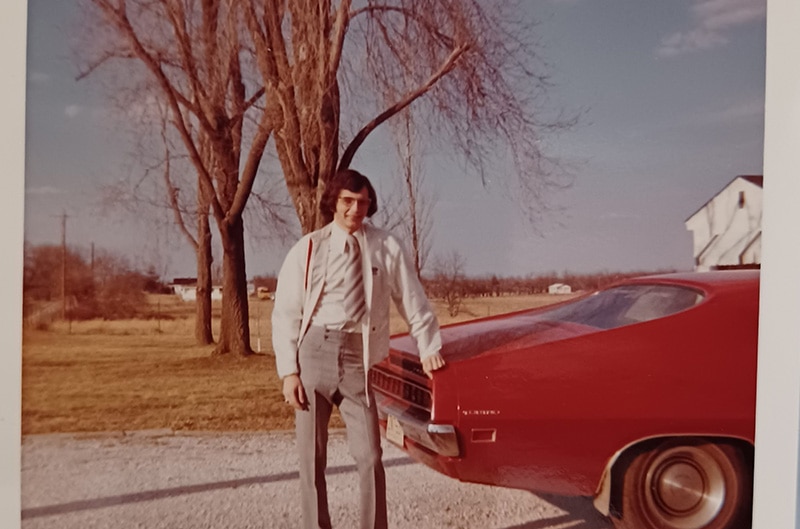 Photo of David standing near the back of his Red Torino