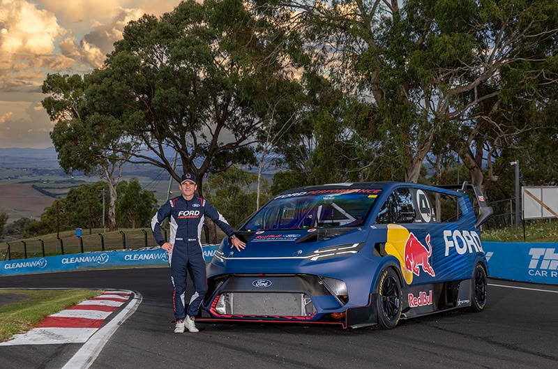 Driver Romain Dumas standing with SuperVan 4.2 on track