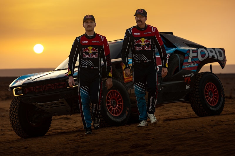 Drivers in front of Raptor in desert