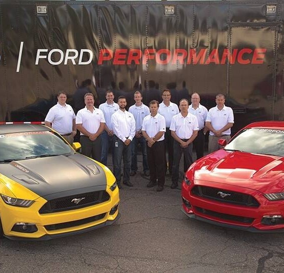 Tech Center Crew Standing behind two Mustangs